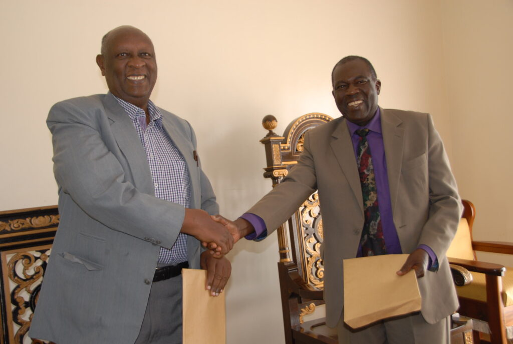 Bunyoro King, Solomon Gafabusa Iguru-left, receives documents from Gulu University academic registrar Geoffrey Lamtoo, after a memorandum of understanding to operationalise Gulu University Hoima campus on December 15 , 2014 at Karuziika palace in Hoima City. Photo by Robert Atuhairwe.