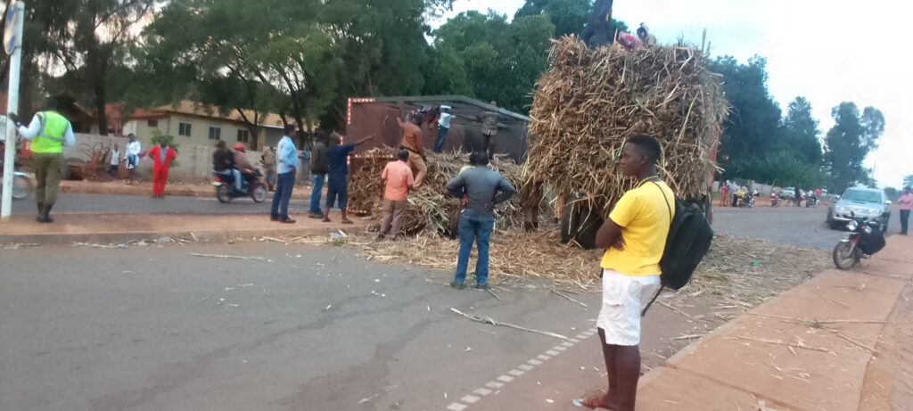 Pedestrians look on as workers clear heaps of cane scattered all over the road at Kijuura in Masindi town on Sunday. Photo by Steven Wandera