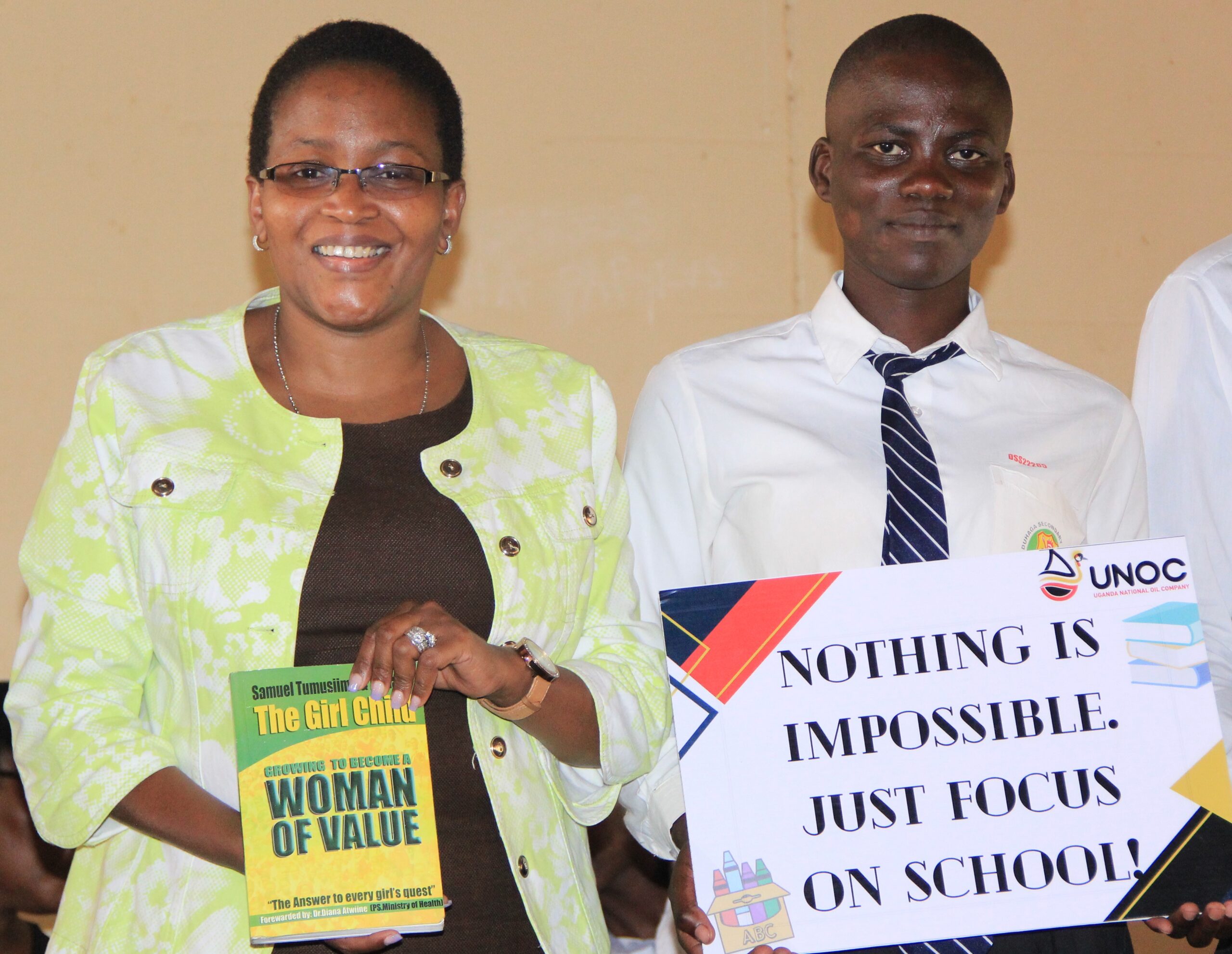 Uganda National Oil Company (UNOC) Proscovia Nnabanja (L) with a student of Duhaga secondary in Hoima. UNOC donated 100 copies of the book that she distributed to secondary schools in Hoima and Kikuube districts in Western Uganda. Photo by Robert Atuhairwe.