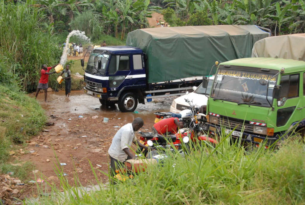 Youth washing cars at River Bigajuka in Lusaka Upper in Hoima City one of the tributaries to River Wambabya. Wetlands in Hoima continue to be degraded due to economic activities despite them providing safe water for the dwellers and acting as habitat for species of aquatic and terrestrial plants and animals. Credit: Robert Atuhairwe/The Albertine Journal.