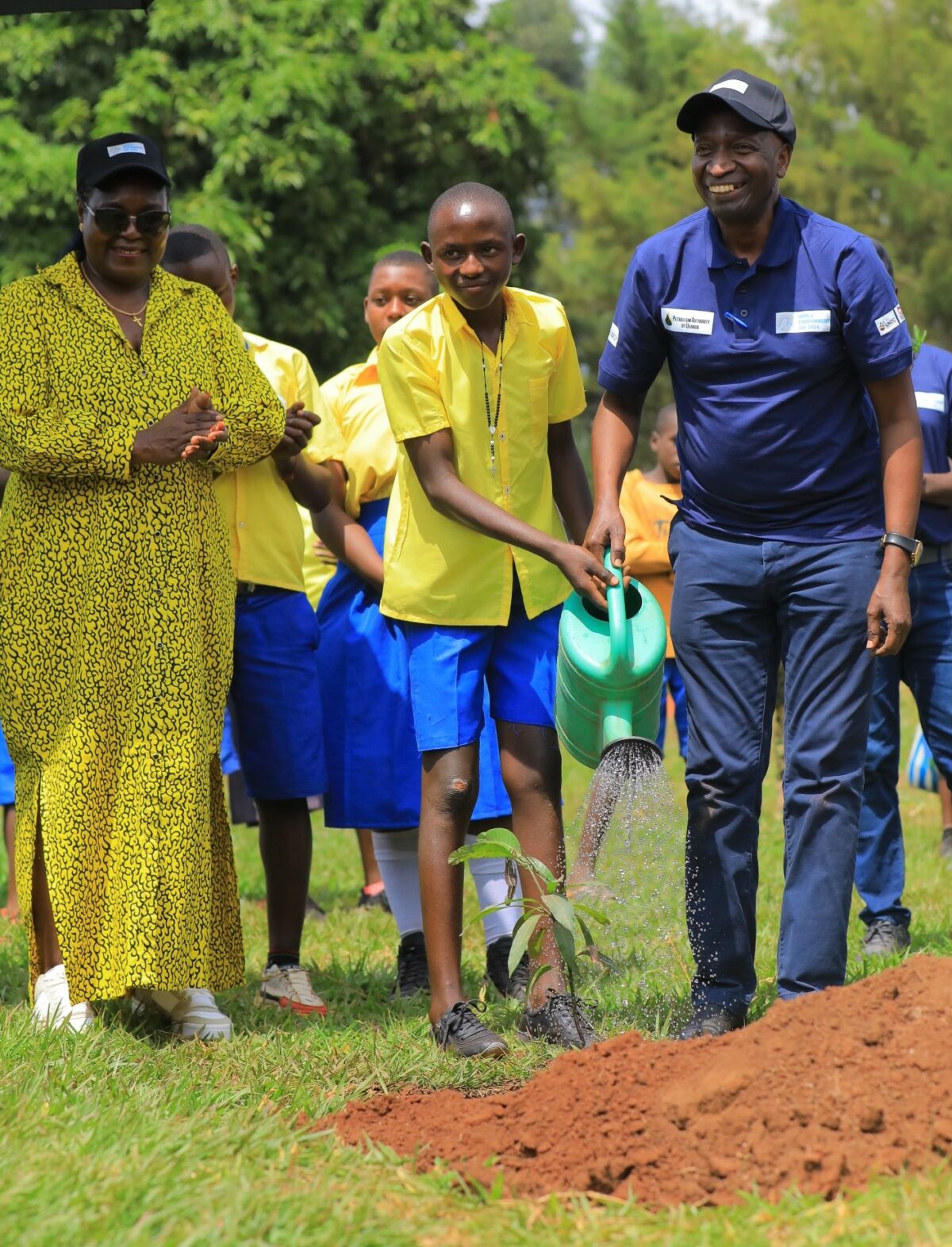 Energy and Mineral Development Minister, Ruth Nankabirwa and Petroleum Authority's Executive Director, Ernest Rubondo, chears on while Mpasaana primary school Head Boy, Bruno Twesigye, waters a planted tree on June 14. Credit: Petroleum Authority of Uganda.