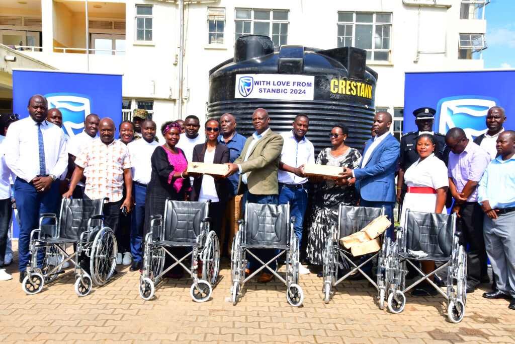 A team from Stanbic Bank Uganda, led by the Customer Experience Manager Peace Nyangoma (centre, in black jacket), handing over wheelchairs and a water tank to Fort Portal Regional Referral Hospital. Credit: Courtesy.