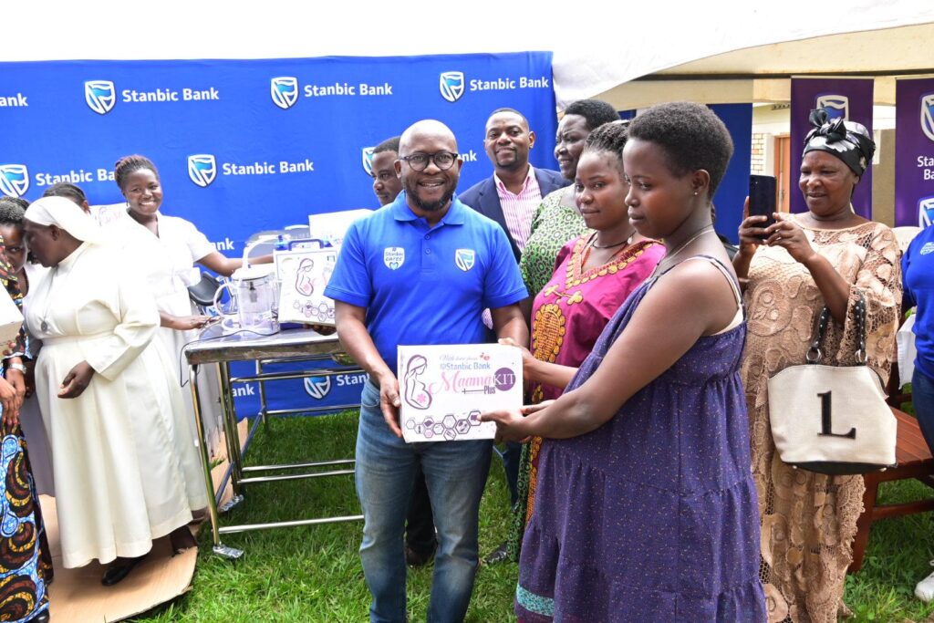 Daniel Ogong (in Blue tshirt), the Head of Marketing at Stanbic Bank, handing over a Mama Kit to an expectant mother at Butende Health Centre III